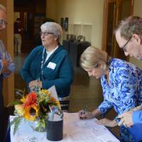 Two alumni checking in, another two alumni enjoying conversation